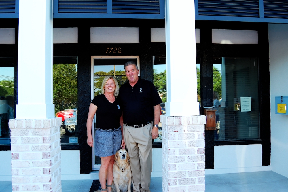 Couple standing with Golden Retriever by their side
