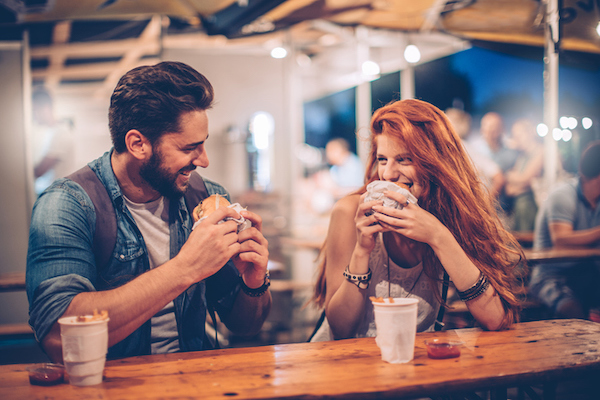 A couple enjoy a burger on a patio A couple enjoy a burger on a patio
